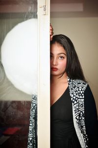 Portrait of young woman standing by window