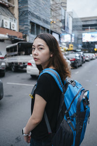 Young woman standing on road in city