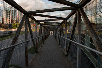 Footbridge in city against sky