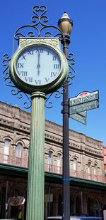 Low angle view of clock on street light against building