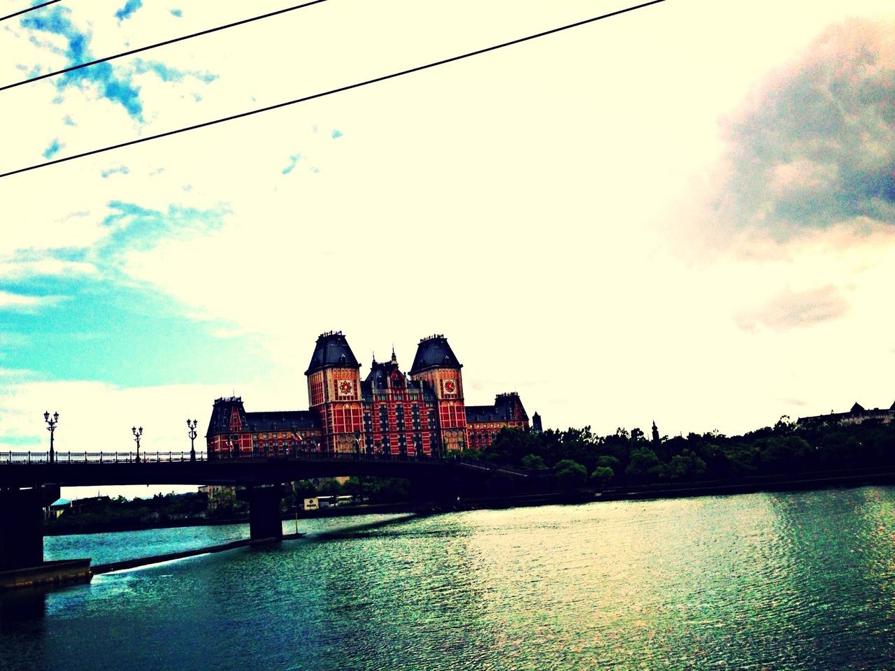 architecture, built structure, water, building exterior, bridge - man made structure, connection, sky, waterfront, river, bridge, cloud - sky, canal, reflection, city, railing, rippled, cloud, outdoors, footbridge, no people