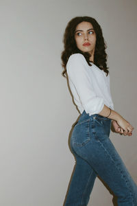 Portrait of young woman standing against white background