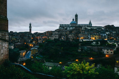 High angle view of city lit up against cloudy sky