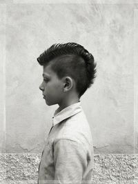 Boy with spiky hair standing by wall