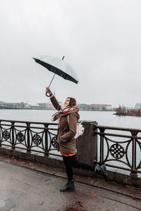 Full length rear view of man standing on railing during rainy season