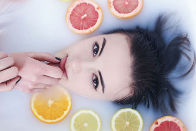 Directly above shot of woman having milk bath with fruits