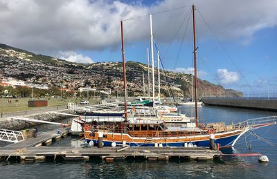 Boats moored at harbor against sky