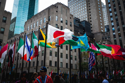 Low angle view of flags against modern buildings in city