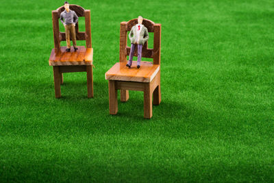 Close-up of male figurines on small chairs at turf