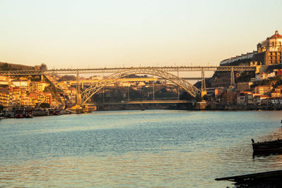 Bridge over river in city against sky during sunset