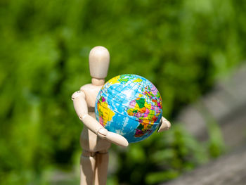 Figurine holding globe against plants