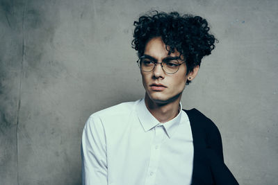 Portrait of young man standing against wall