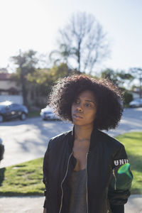 Portrait of young woman standing against car