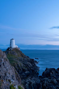 Lighthouse by sea against blue sky