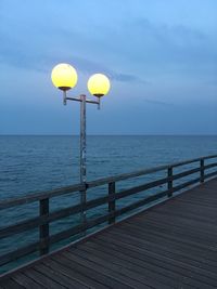 Street light by sea against sky