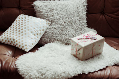 Gift box and pillows on sofa in living room at home