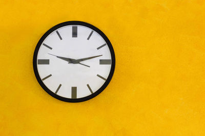 Low angle view of clock on yellow wall