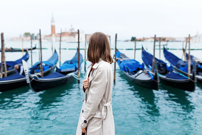 Girl in a dress and coat on the background of the canal and gondola