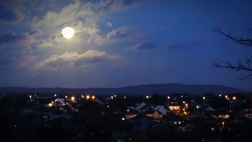 Illuminated town against sky at night