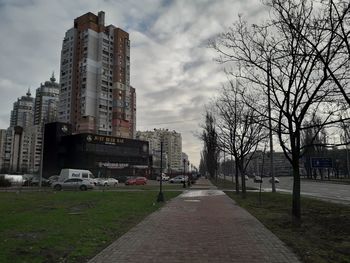 Road by buildings against sky in city