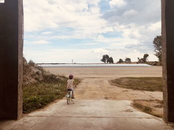 Rear view of girl riding bicycle against sky