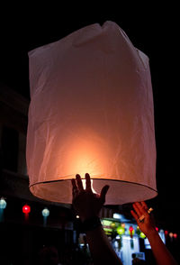 People holding illuminated lantern at night