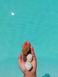 Close-up of hand holding ice cream against blue background