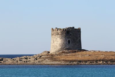 Castle by sea against clear blue sky
