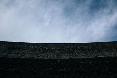 Low angle view of birds flying over roof against sky