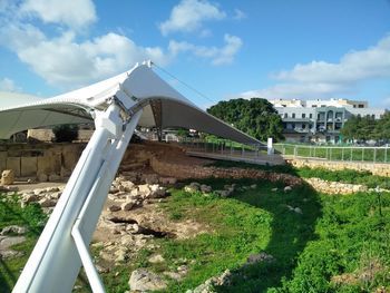 Built structure on field by buildings against sky