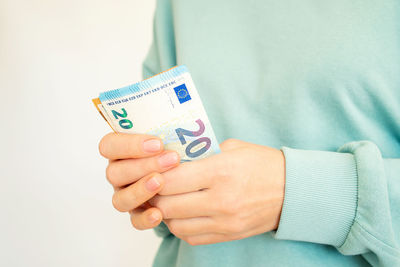 Midsection of woman holding paper currency against white background
