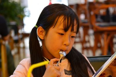 Close-up of girl reading book while eating at cafe