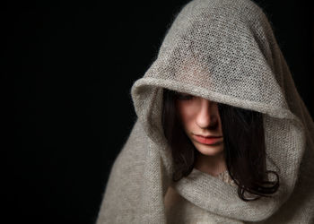 Close-up of woman wearing hat against black background