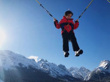 Boy jumping in mountains against clear sky