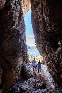 Rear view of women standing on rock formation in sea