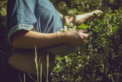 Woman looking away while sitting on tree trunk