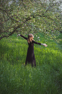 Woman spreading arms with joy under blooming trees scenic photography