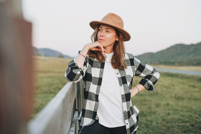 Young woman looking away while standing on field