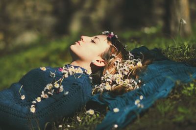 Young woman with flowers lying down on field