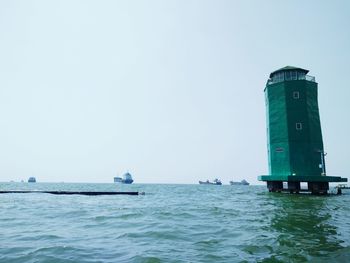 Lighthouse sailing on sea against clear sky