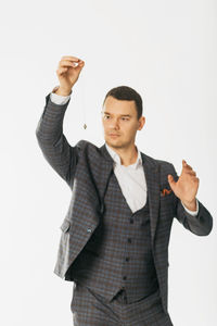 Young man looking away while standing against white background