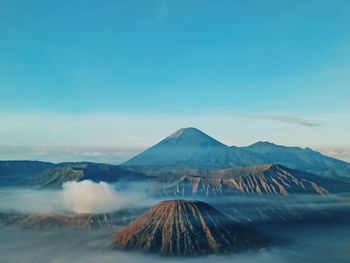 Scenic view of volcanic mountain range against blue sky