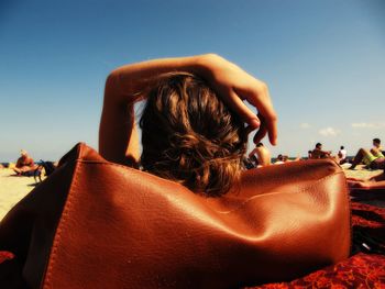 Rear view of woman at beach against clear sky