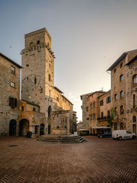 View of well and old building in city against sky, medieval tuscany san gimignano, italy