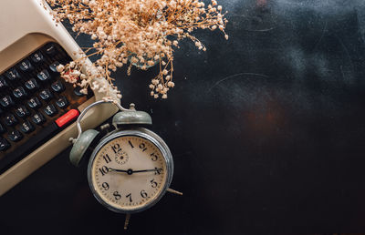 Close-up of alarm clock by typewriter on table