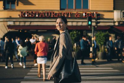 Portrait of smiling young woman on road in city