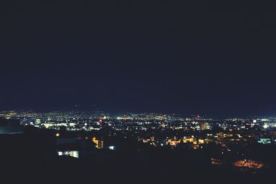 Illuminated cityscape against clear sky at night