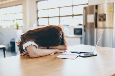 Woman using phone while sitting on table