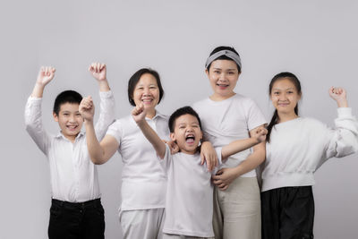 Portrait of happy friends standing against white background