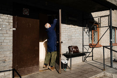 Rear view of man standing against wall in building